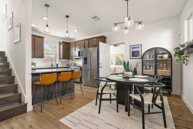 kitchen with pendant lighting, tasteful backsplash, stainless steel appliances, and light wood-type flooring