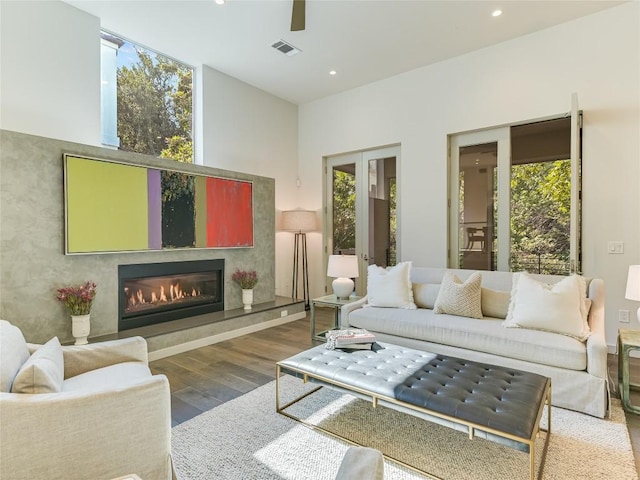 living room with a glass covered fireplace, plenty of natural light, and wood finished floors