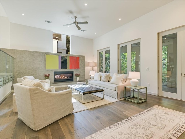 living area featuring a glass covered fireplace, wood finished floors, visible vents, and recessed lighting