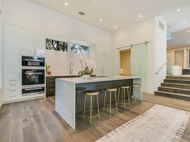 kitchen featuring a kitchen island, wood-type flooring, white cabinetry, and a barn door