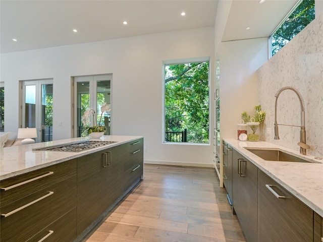 kitchen featuring modern cabinets, light stone counters, light wood-style floors, a sink, and recessed lighting