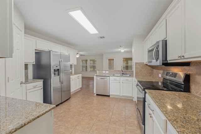 kitchen with light stone counters, white cabinetry, light tile patterned floors, and stainless steel appliances