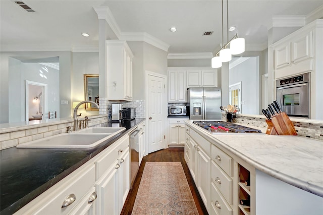 kitchen featuring appliances with stainless steel finishes, decorative light fixtures, decorative backsplash, sink, and light stone counters