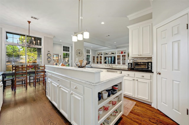 kitchen with decorative light fixtures, white cabinets, dark wood-type flooring, ornamental molding, and a kitchen island