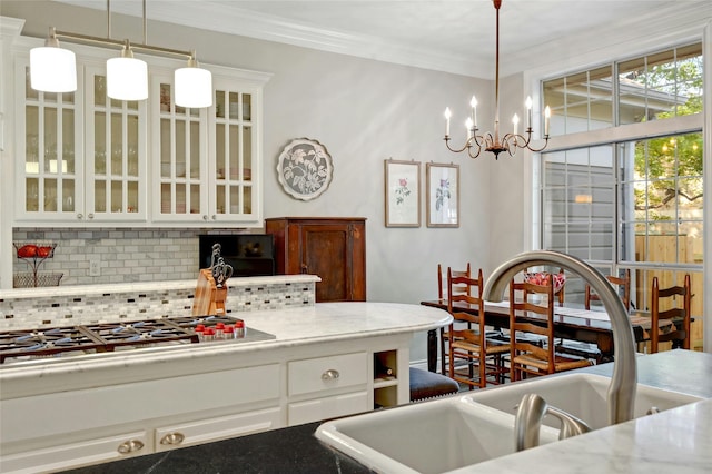 kitchen featuring decorative light fixtures, sink, white cabinetry, and stainless steel gas cooktop