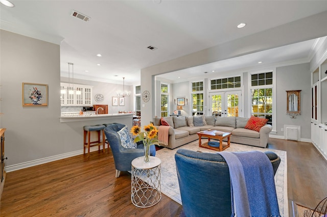 living room featuring a chandelier, dark hardwood / wood-style flooring, ornamental molding, and french doors