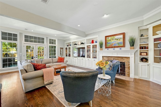 living room with wood-type flooring, a brick fireplace, french doors, ornamental molding, and built in features