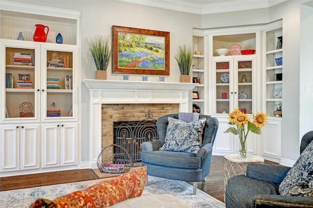 living area with hardwood / wood-style flooring, built in shelves, crown molding, and a fireplace