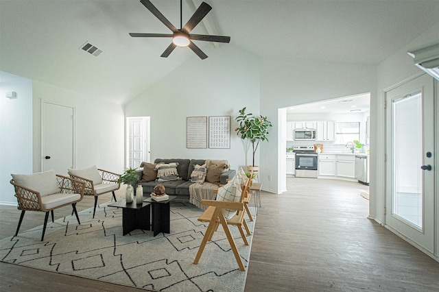 living room with light hardwood / wood-style floors, sink, lofted ceiling with beams, and ceiling fan