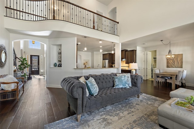 living room featuring a high ceiling, a notable chandelier, and dark hardwood / wood-style flooring