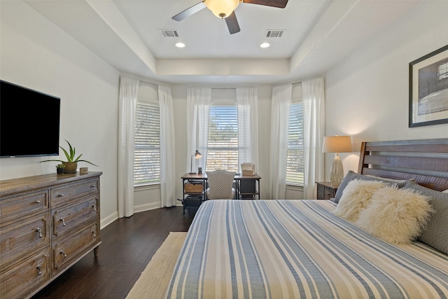 bedroom featuring dark hardwood / wood-style floors, ceiling fan, and a tray ceiling