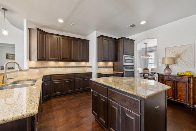 kitchen with dark brown cabinetry, sink, dark wood-type flooring, and decorative light fixtures