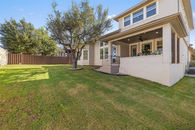 rear view of property with ceiling fan and a lawn