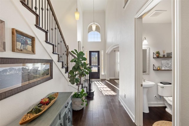 foyer featuring crown molding, a towering ceiling, and dark hardwood / wood-style flooring