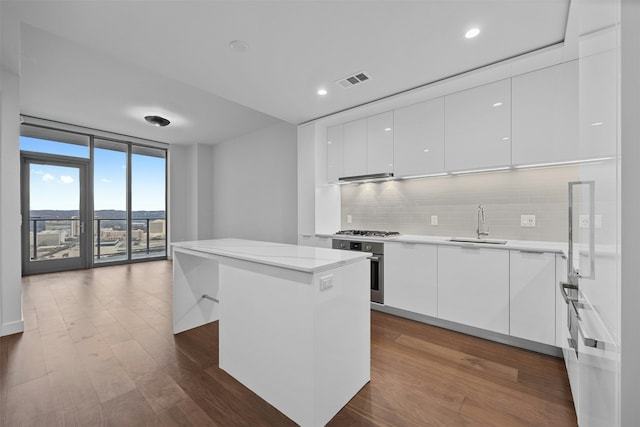 kitchen with sink, expansive windows, white cabinets, and a center island