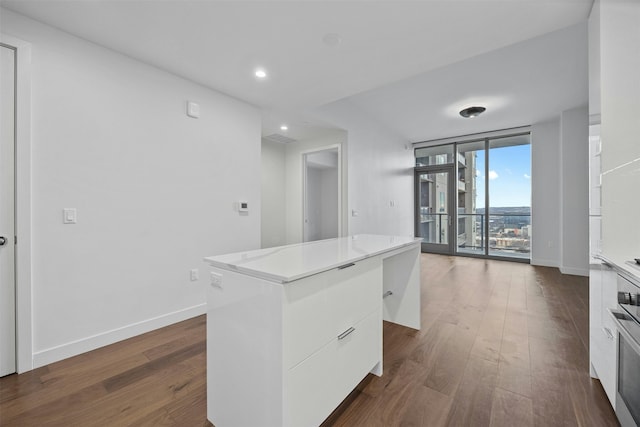 kitchen featuring a wall of windows, dark hardwood / wood-style floors, a center island, and white cabinets