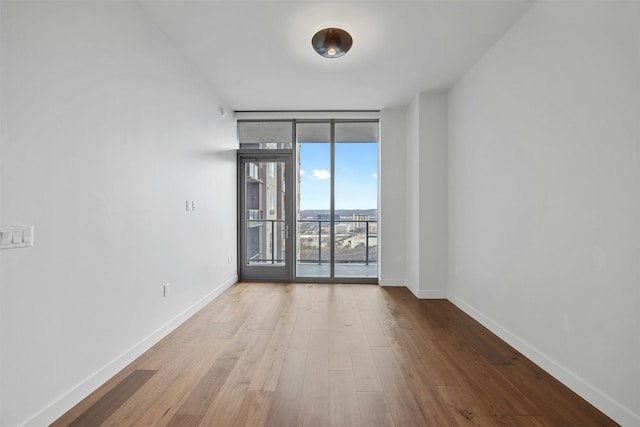 unfurnished room featuring expansive windows and light hardwood / wood-style floors