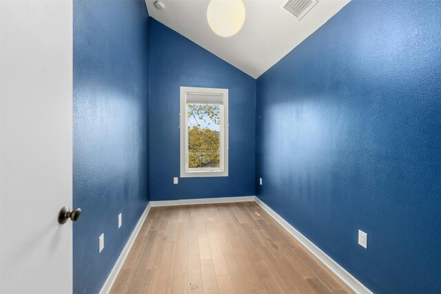 unfurnished room featuring hardwood / wood-style flooring and vaulted ceiling