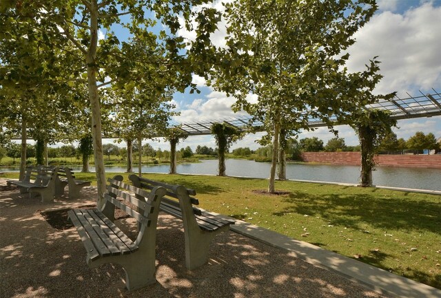 view of home's community featuring a water view, a pergola, and a yard