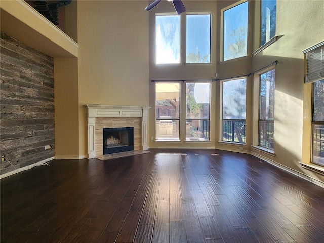 unfurnished living room with a high ceiling, a tile fireplace, and dark hardwood / wood-style flooring