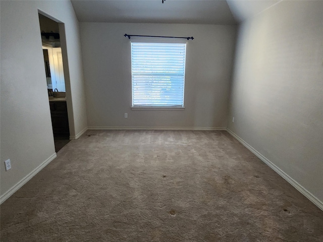 spare room featuring sink, vaulted ceiling, and carpet