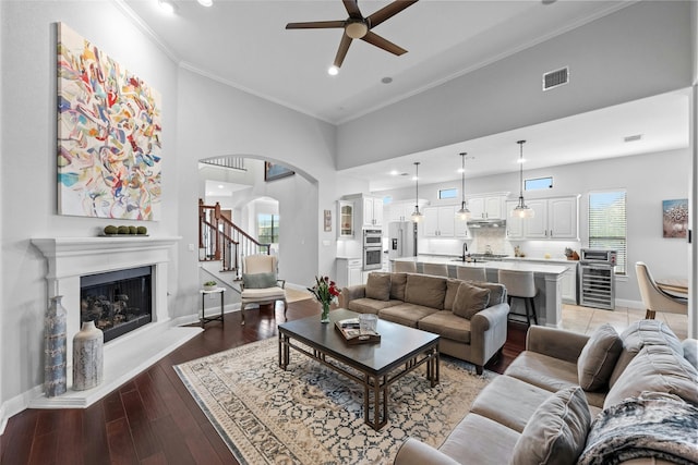 living room featuring crown molding, wine cooler, ceiling fan, sink, and hardwood / wood-style flooring