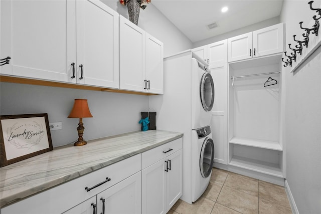 washroom with light tile patterned floors, cabinets, and stacked washer and clothes dryer