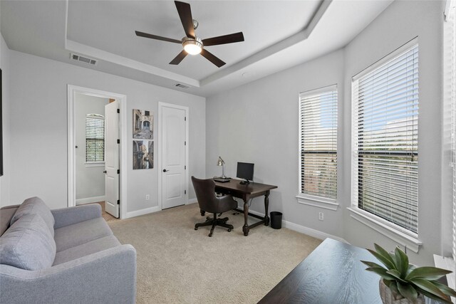 office featuring ceiling fan, a raised ceiling, and light carpet