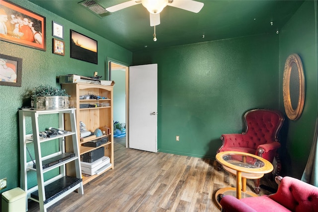 living area with hardwood / wood-style flooring and ceiling fan