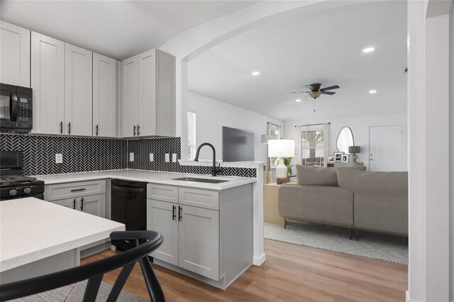 kitchen featuring ceiling fan, sink, light wood-type flooring, gray cabinets, and black appliances