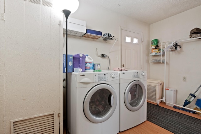 laundry area featuring washing machine and clothes dryer, a textured ceiling, and hardwood / wood-style flooring