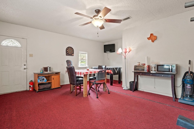 carpeted dining area with a textured ceiling and ceiling fan