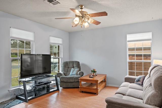 living room featuring light wood-type flooring, plenty of natural light, and a textured ceiling