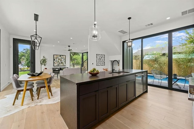 kitchen with sink, pendant lighting, dark brown cabinetry, and a kitchen island with sink