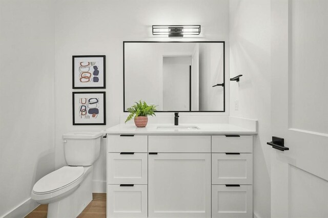 bathroom with hardwood / wood-style floors, toilet, and vanity