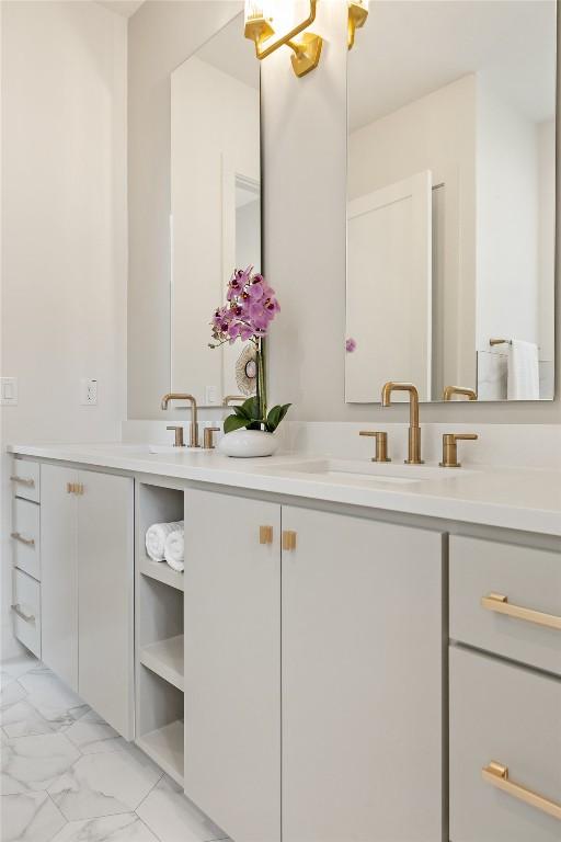 bathroom with marble finish floor, a sink, and double vanity