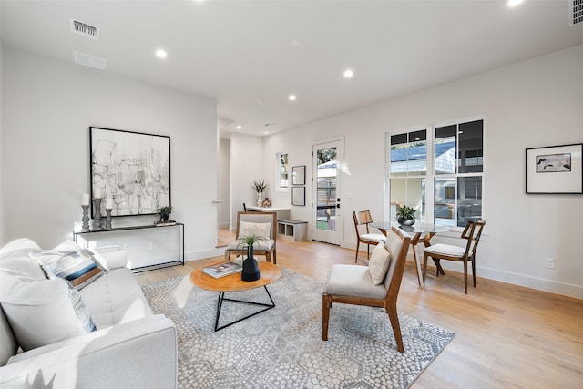 living room featuring light wood-type flooring, visible vents, and recessed lighting