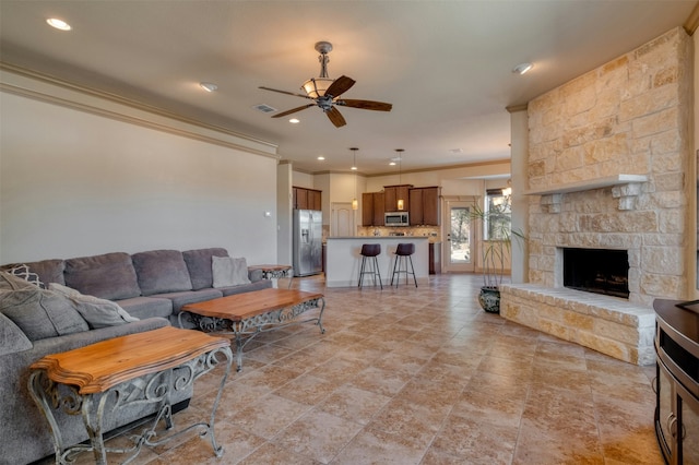 living room featuring crown molding, a fireplace, and ceiling fan