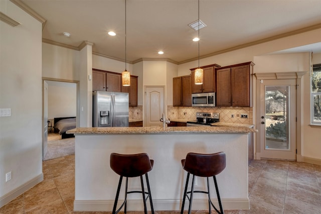 kitchen with decorative light fixtures, a center island with sink, appliances with stainless steel finishes, and a breakfast bar