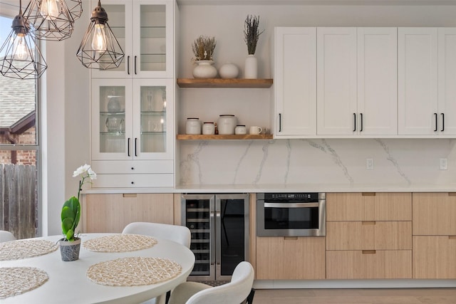 kitchen with wine cooler, hanging light fixtures, oven, light stone countertops, and decorative backsplash