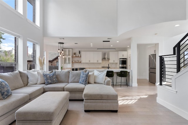 living room featuring a towering ceiling and light wood-type flooring