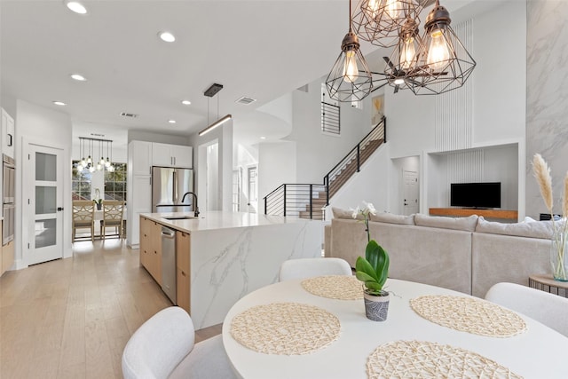 dining space with sink, a notable chandelier, and light wood-type flooring