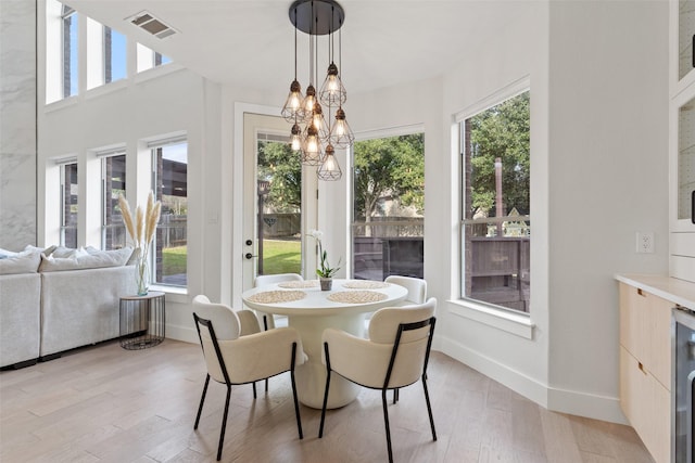 sunroom / solarium featuring wine cooler and a chandelier