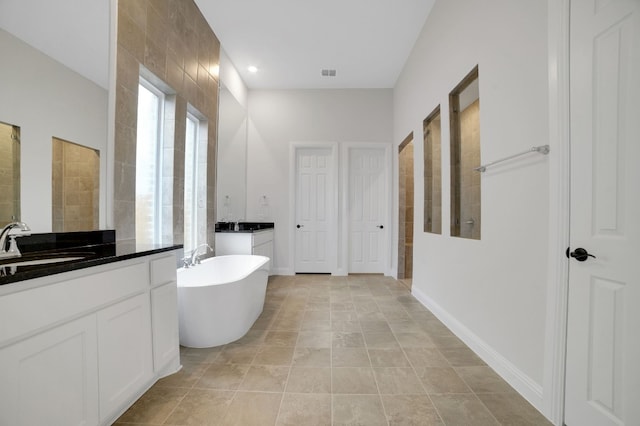 17604 Arend Path, Pflugerville, TX 78660 - full bathroom featuring two vanities, a soaking tub, a tile shower, and baseboards