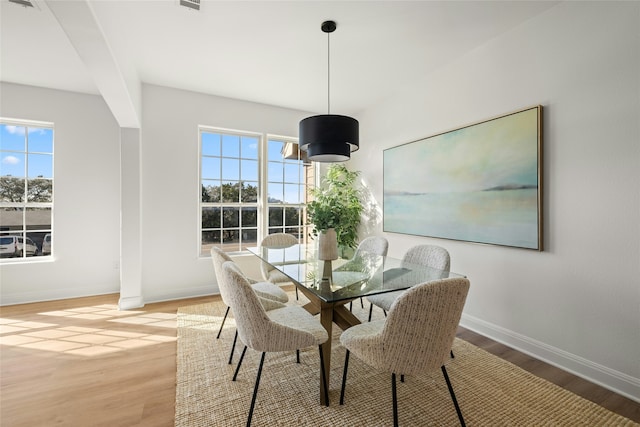 dining room with light hardwood / wood-style flooring and beam ceiling