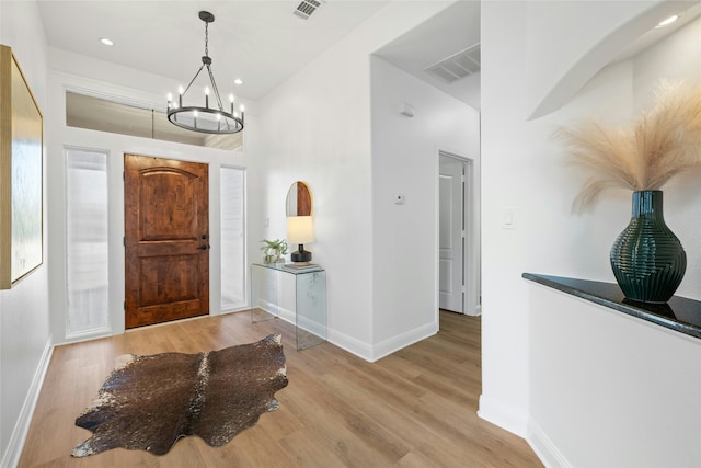 foyer featuring light wood-type flooring and a chandelier