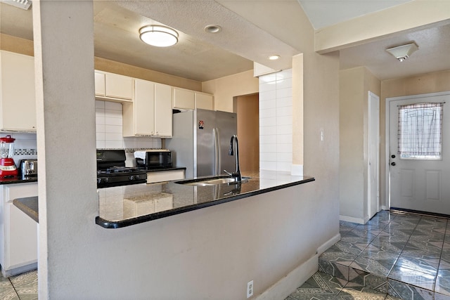 kitchen with black appliances, tasteful backsplash, white cabinets, dark stone countertops, and kitchen peninsula