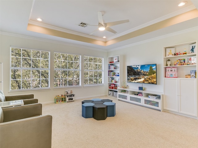 interior space with ornamental molding, carpet flooring, a raised ceiling, built in features, and ceiling fan