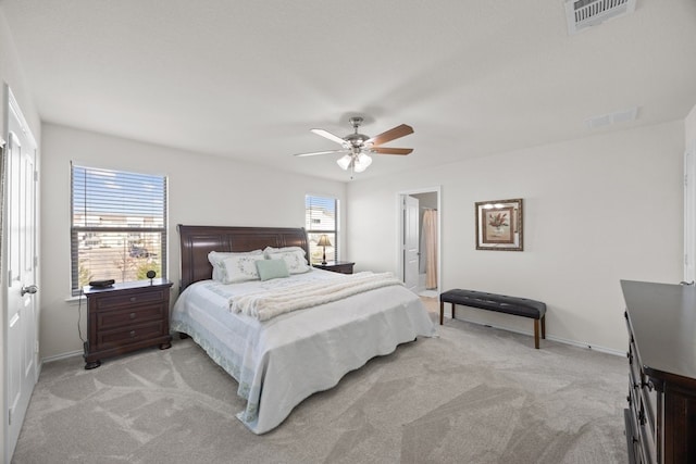 bedroom featuring ceiling fan, ensuite bathroom, and light carpet