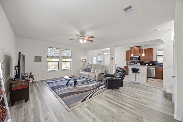 17106 Gibbons Path, Round Rock, TX 78664 - living room with arched walkways, ceiling fan, light wood finished floors, and plenty of natural light